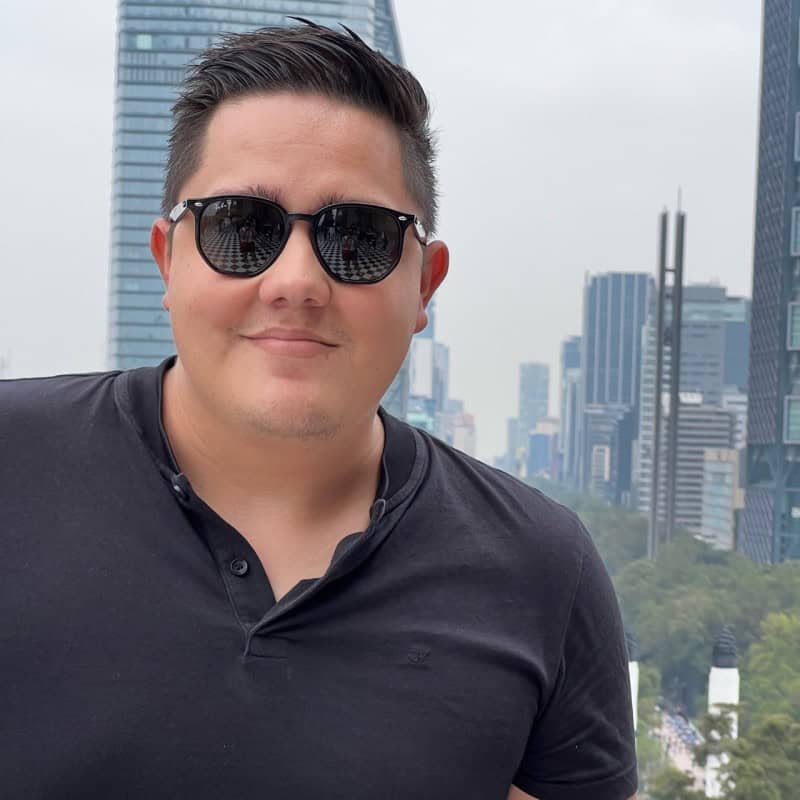 Man wearing sunglasses in urban city with skyscrapers in background.